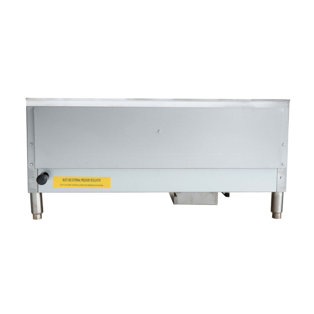 A stainless steel commercial flat top grill or thermostatic griddle shown from the back, featuring a yellow warning label and metal legs, set against a plain white background.