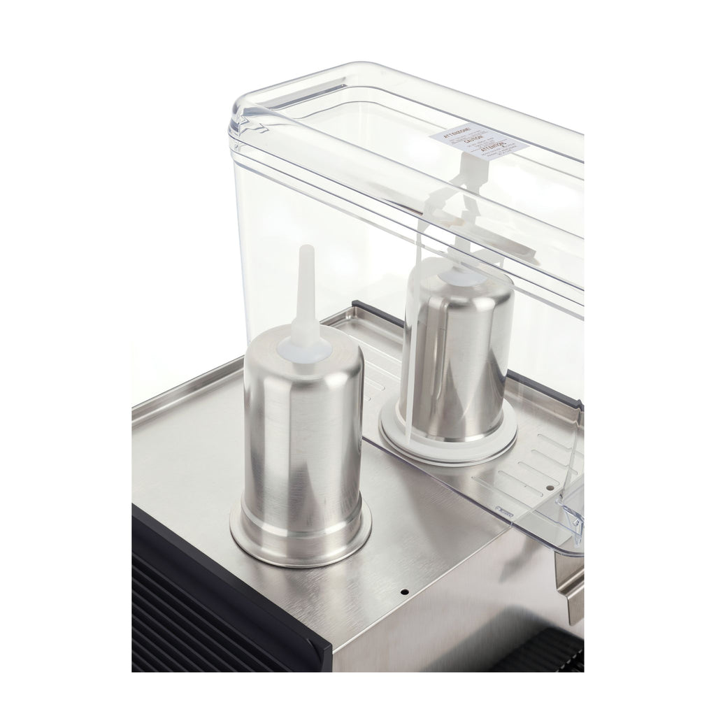 Close-up of a stainless steel machine component with two clear cylindrical containers and transparent lids on a white background.