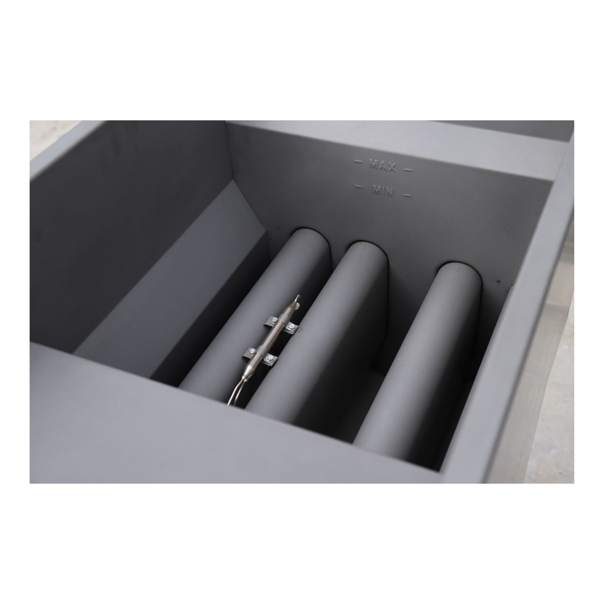 Close-up of floor fryer burner tubes chamber with three vertical cylindrical tubes and a small metal rod inside.
