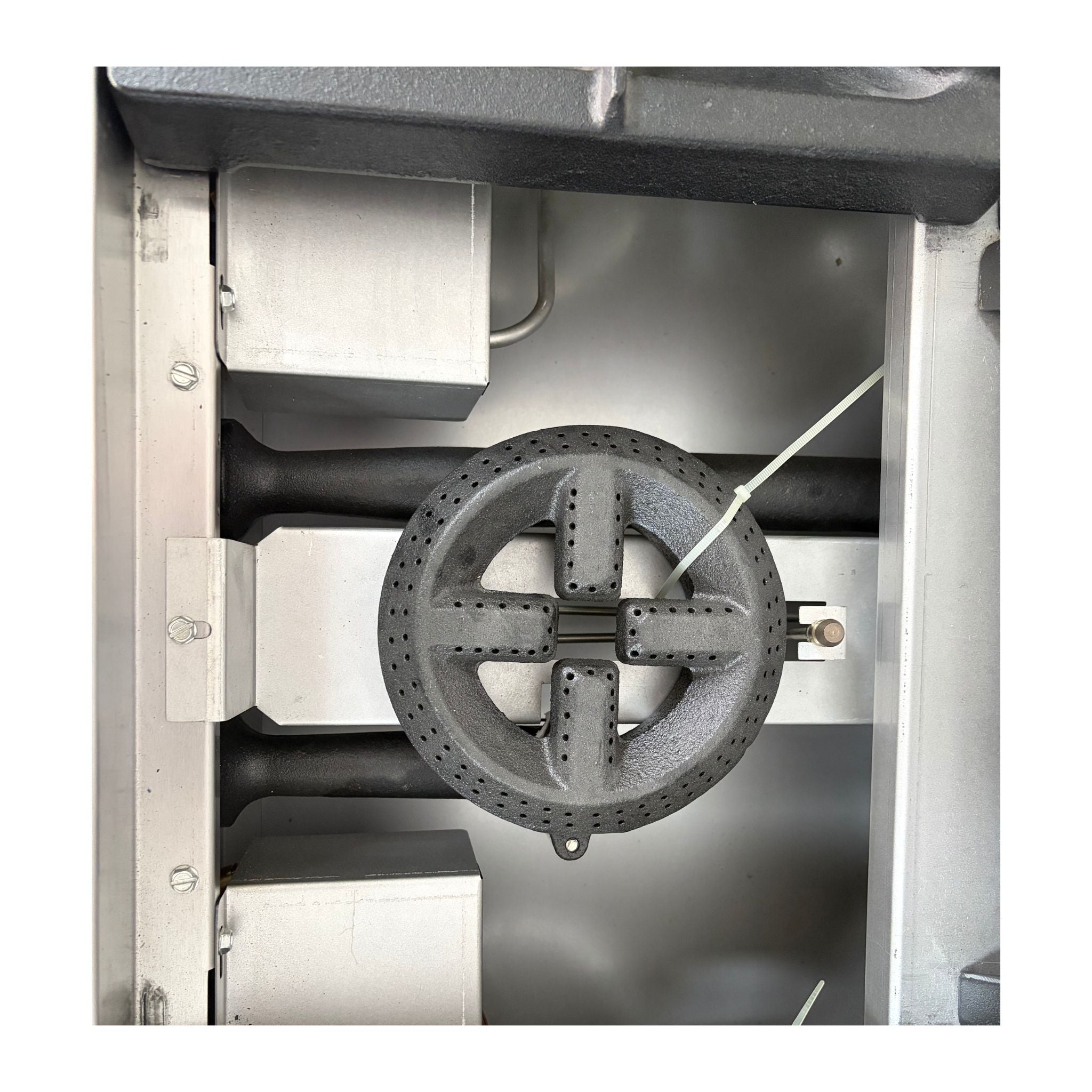 A close-up view of a dark gray cast iron gas burner assembly inside a stainless steel appliance or furnace chamber.